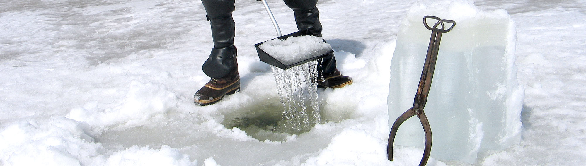 Large ice tongs resting against a two-foot chunk of ice with the Darkhouse Dipper in the background